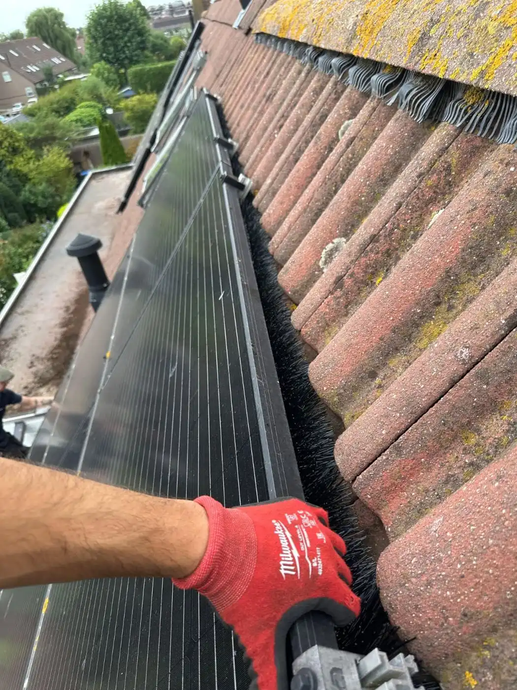 Monteur plaatst een borstel langs de rand van zonnepanelen
